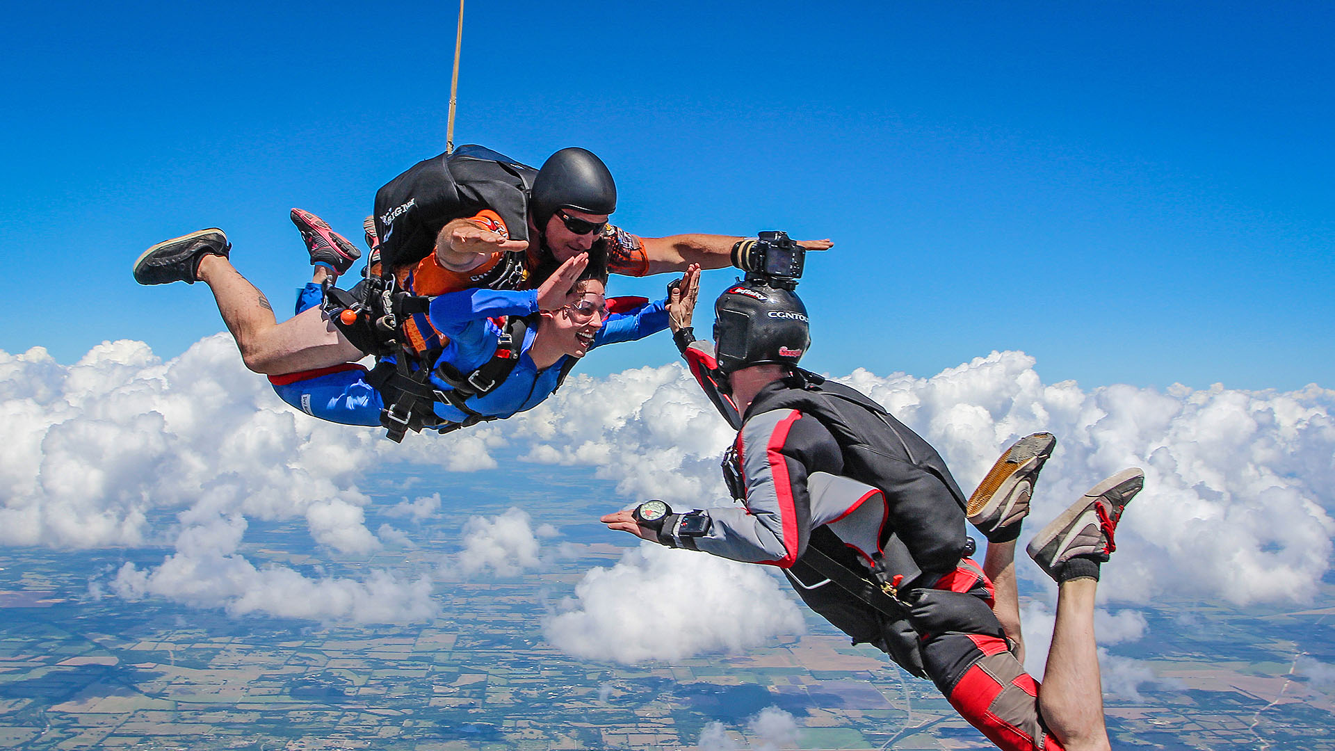 Skydiving videographer high-fiving the student over Skydive Spaceland Dallas